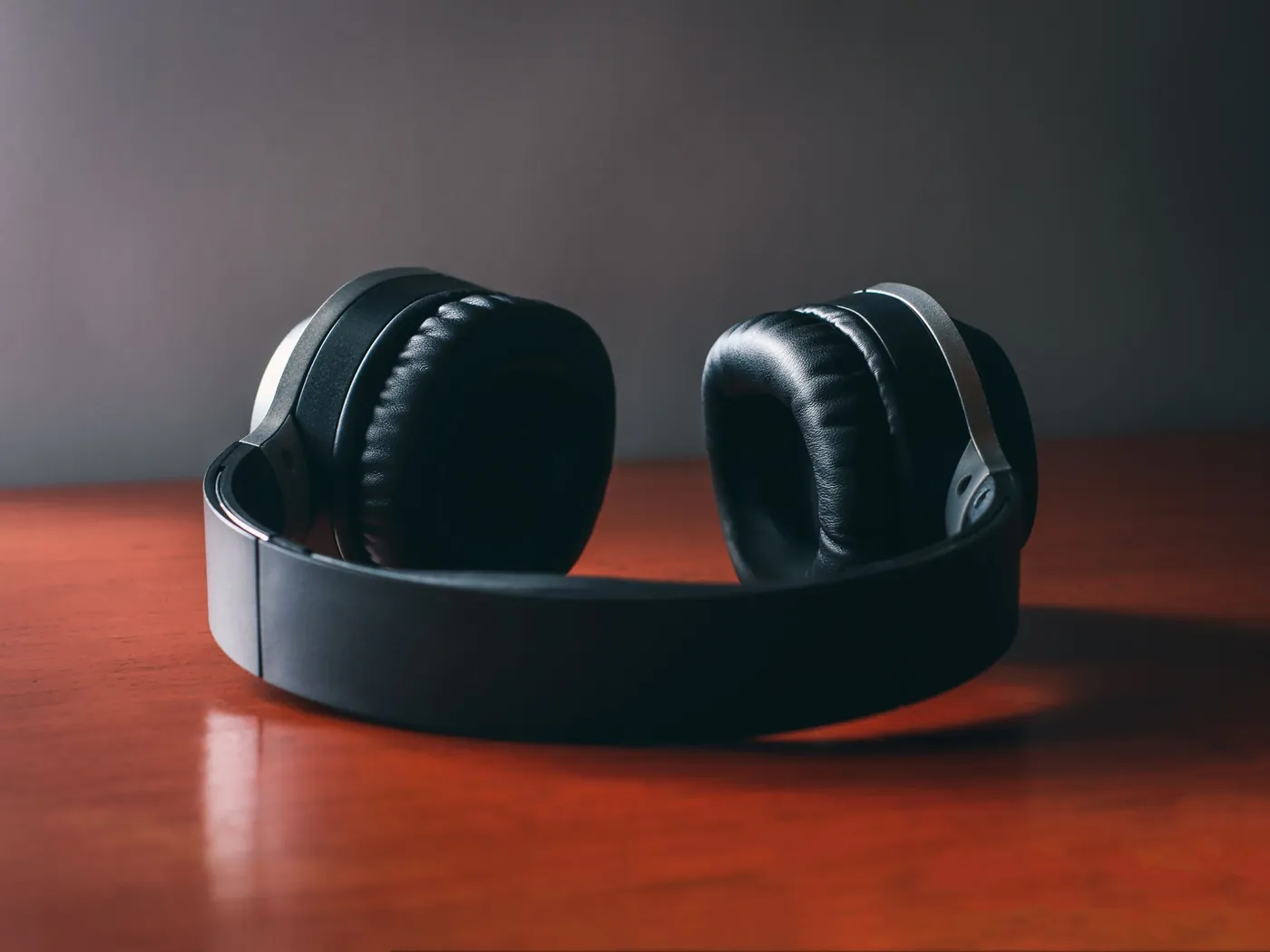A pair of over-ear headphones resting on a warm wooden surface