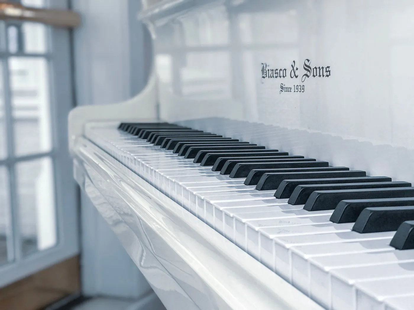 A white piano beside a window in a quiet, light-filled room