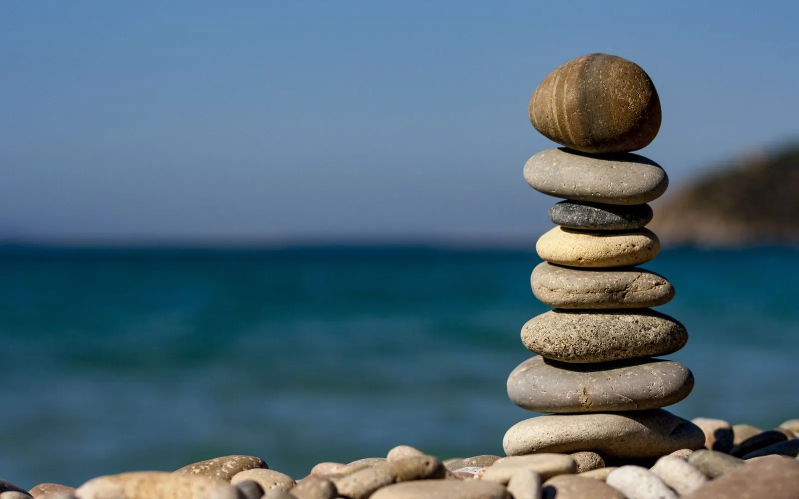 A stone cairn balanced above calm sea water