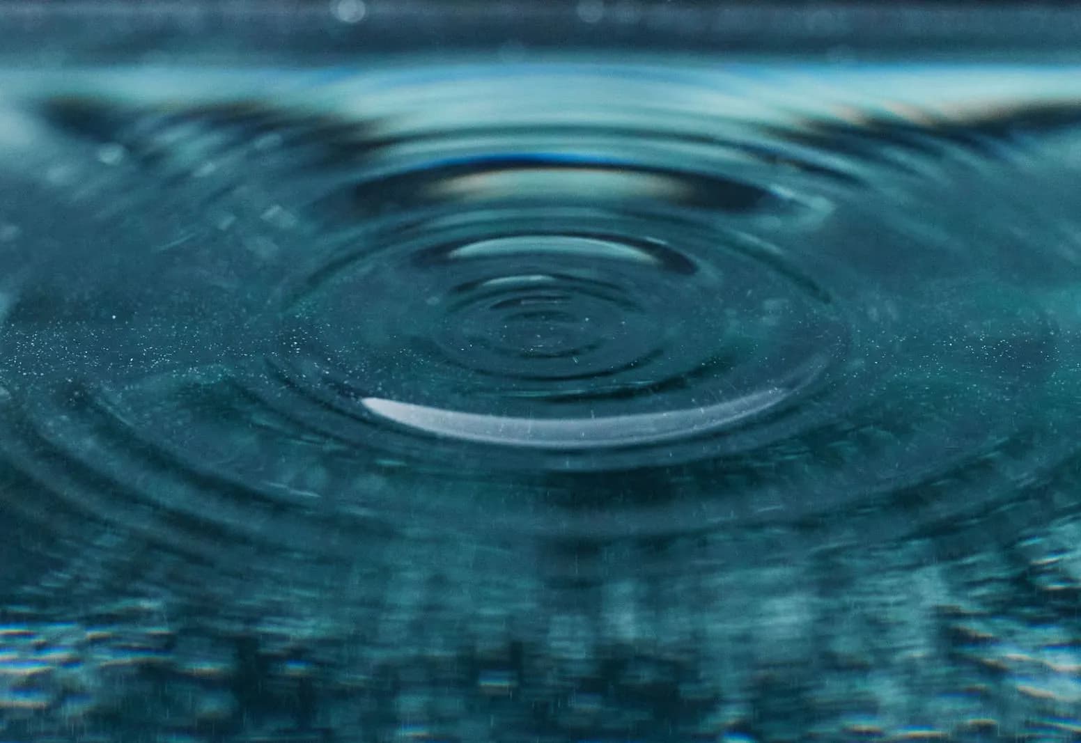 Concentric ripples spreading across teal water